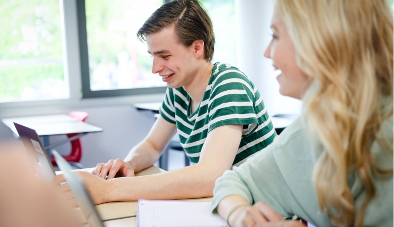 Twee studenten van hbo bedrijfskunde aan tafel tijdens een projectgroep overleg