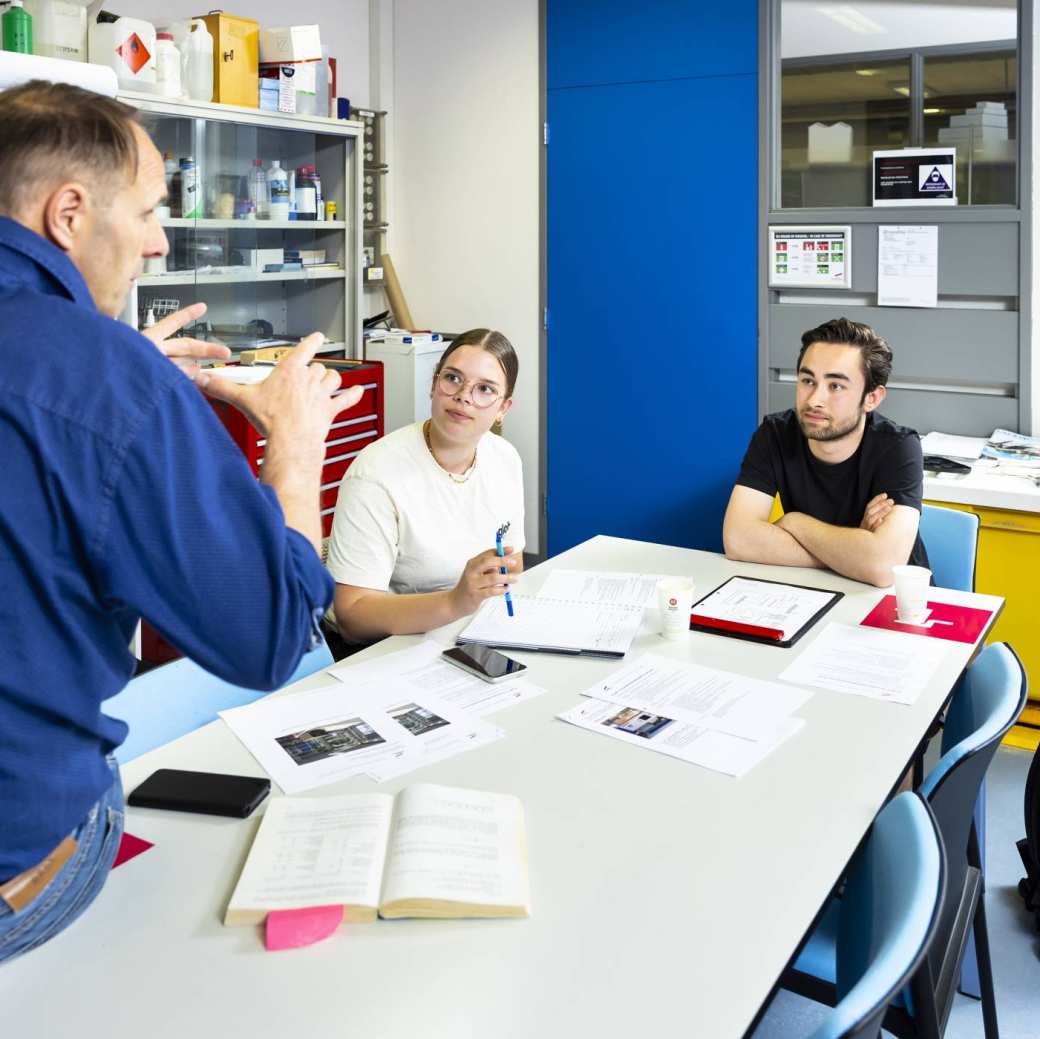 docent legt iets uit aan 2 studenten