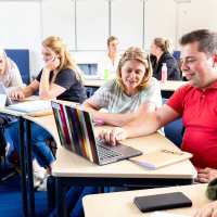 Mensen kijken op een laptop in een lokaal