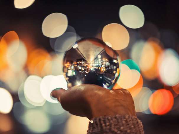Een glazen bol met een stad op een hand met kleurige achtergrond lichtjes