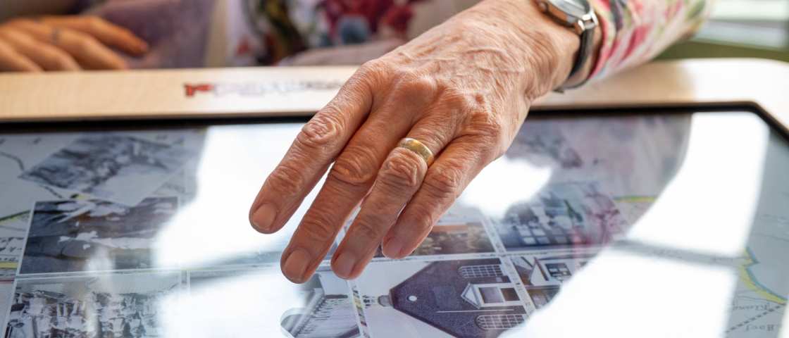 Hand van oudere raakt digitale belevenistafel aan