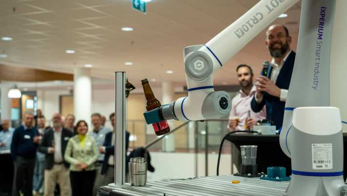 Het iXperium is geopend op 16 april. Een cobot pakt het door AI samengestelde biertje en schenkt een glas in.