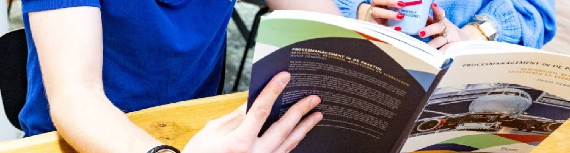 Studenten Facility Management lezen samen in een studieboek