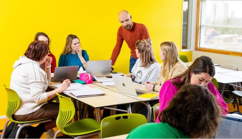 Twee studenten die serieus aan het werk zijn achter een laptop in de mediatheek.