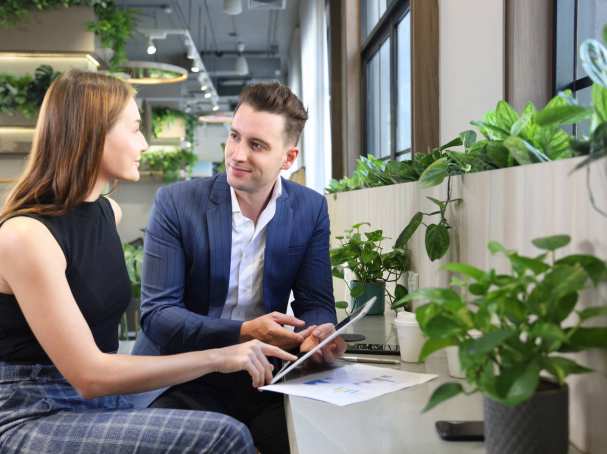 Foto van twee mensen in overleg met een tablet in kantoorruimte met planten voor projectpagina van het ass. lectoraat Sustianable Finance & Tax.