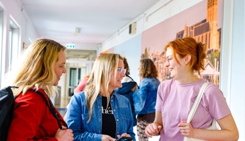 Vijf studenten die aan het overleggen zijn aan een houten tafel