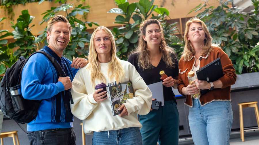 Staande groep studenten lachen en wandelen richting camera