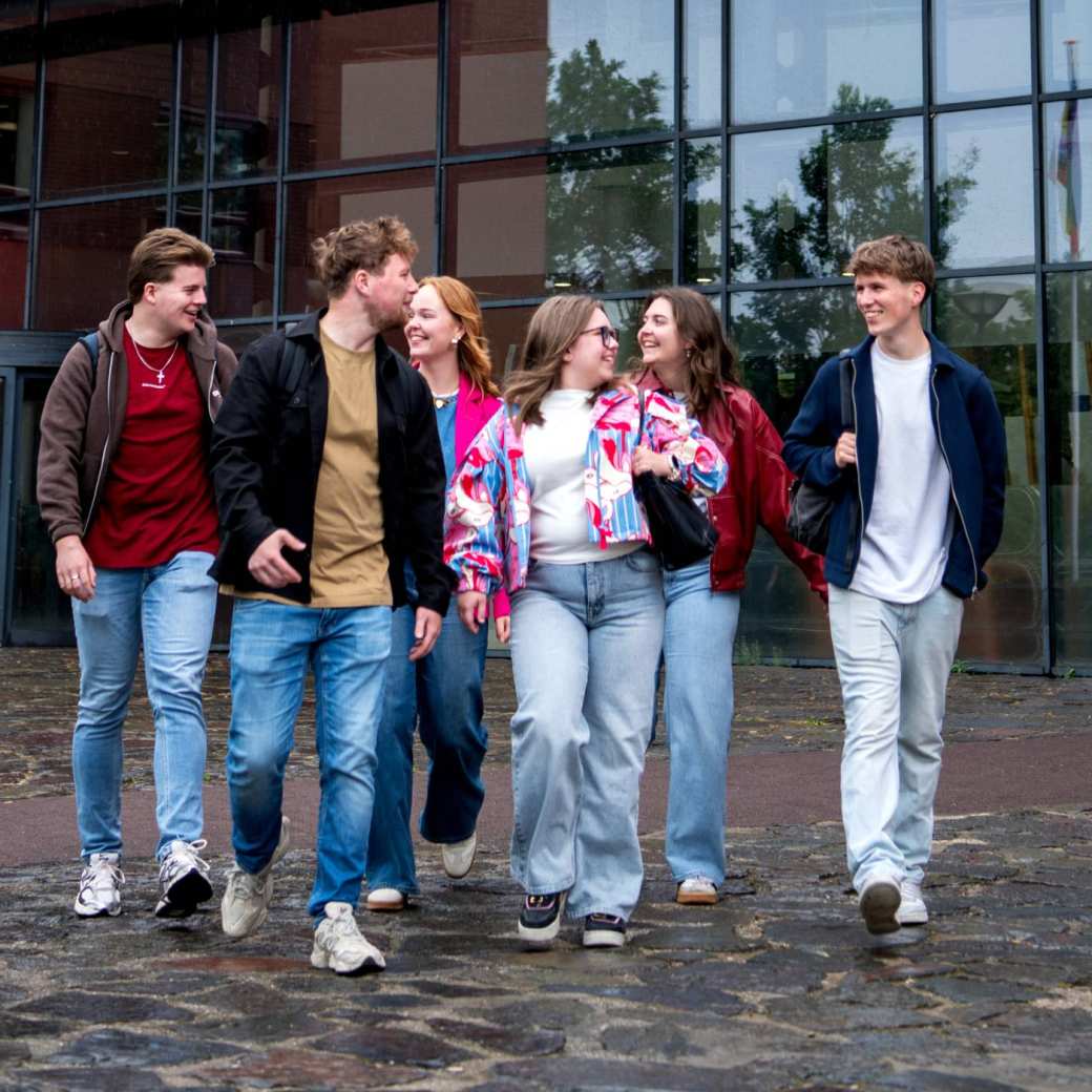 Een groep studenten loopt naar buiten op de HAN campus en kijkt elkaar aan.