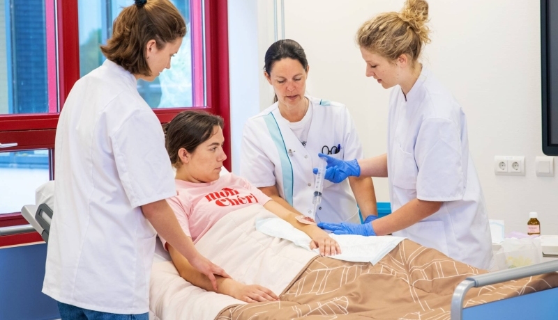 Studenten en docent Verpleegkunde bezig tijdens praktijkles