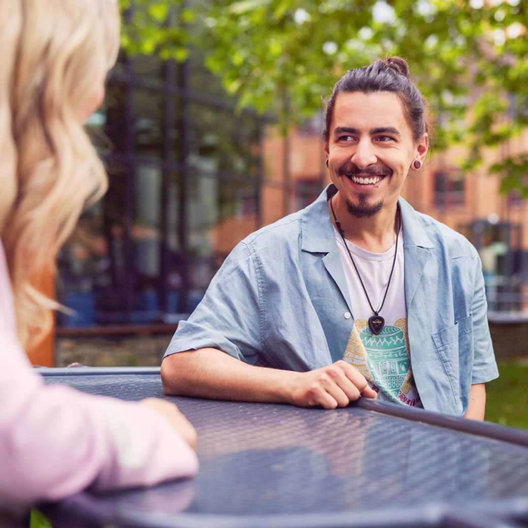 werving voltijd campagne, twee studenten in gesprek aan een picnictafel in de binnentuin.