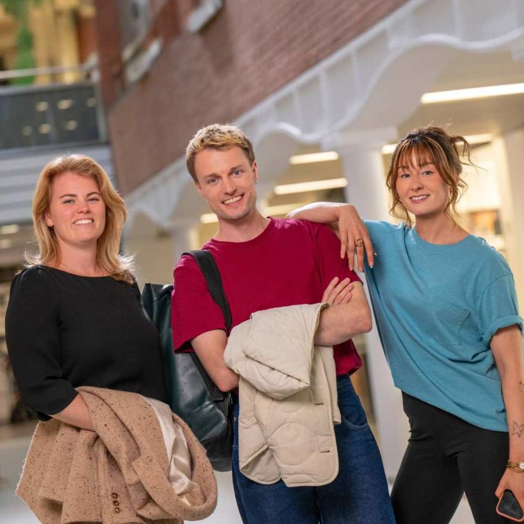 Groep studenten staat in hal met jassen uit en lachen