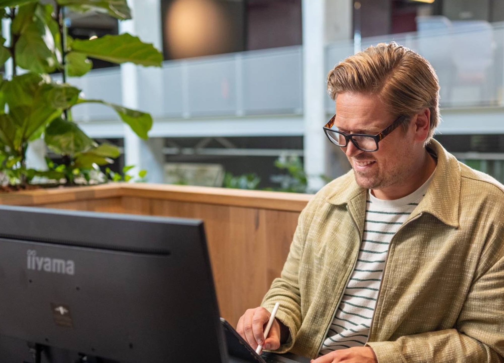 Man met bril op het werk achter een bureau aan het tekenen op tablet
