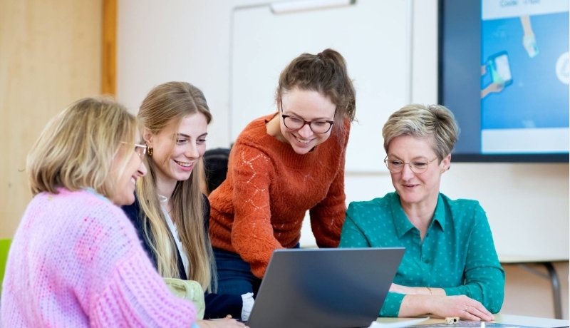 Vier studenten kijken samen naar het scherm (laptop). 