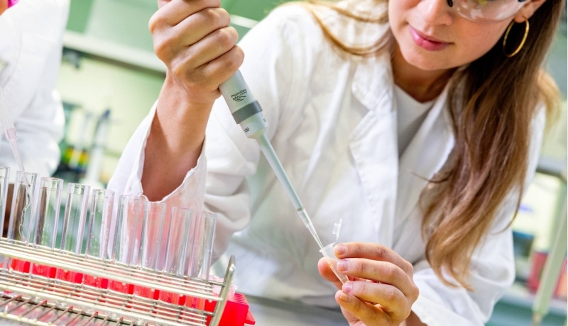 Student in het lab met reageerbuisjes en een pipet