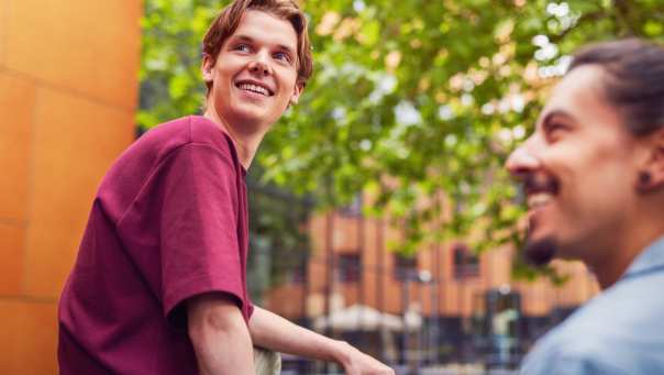 werving voltijd campagne, studente met bordeaux rood t-shirt zit op een picnictafel in de binnentuin.