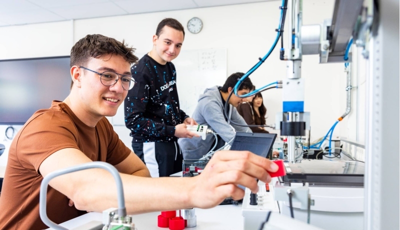 Twee elektrotechniekstudenten werken samen aan een PLC.