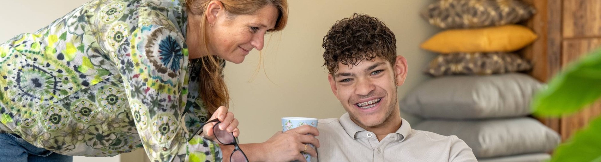 Moeder en zoon lachen terwijl ze hangen in een stoel en bezig zijn op de laptop. 