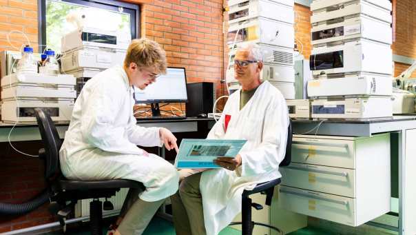docent geeft uitleg aan student in chemie lab