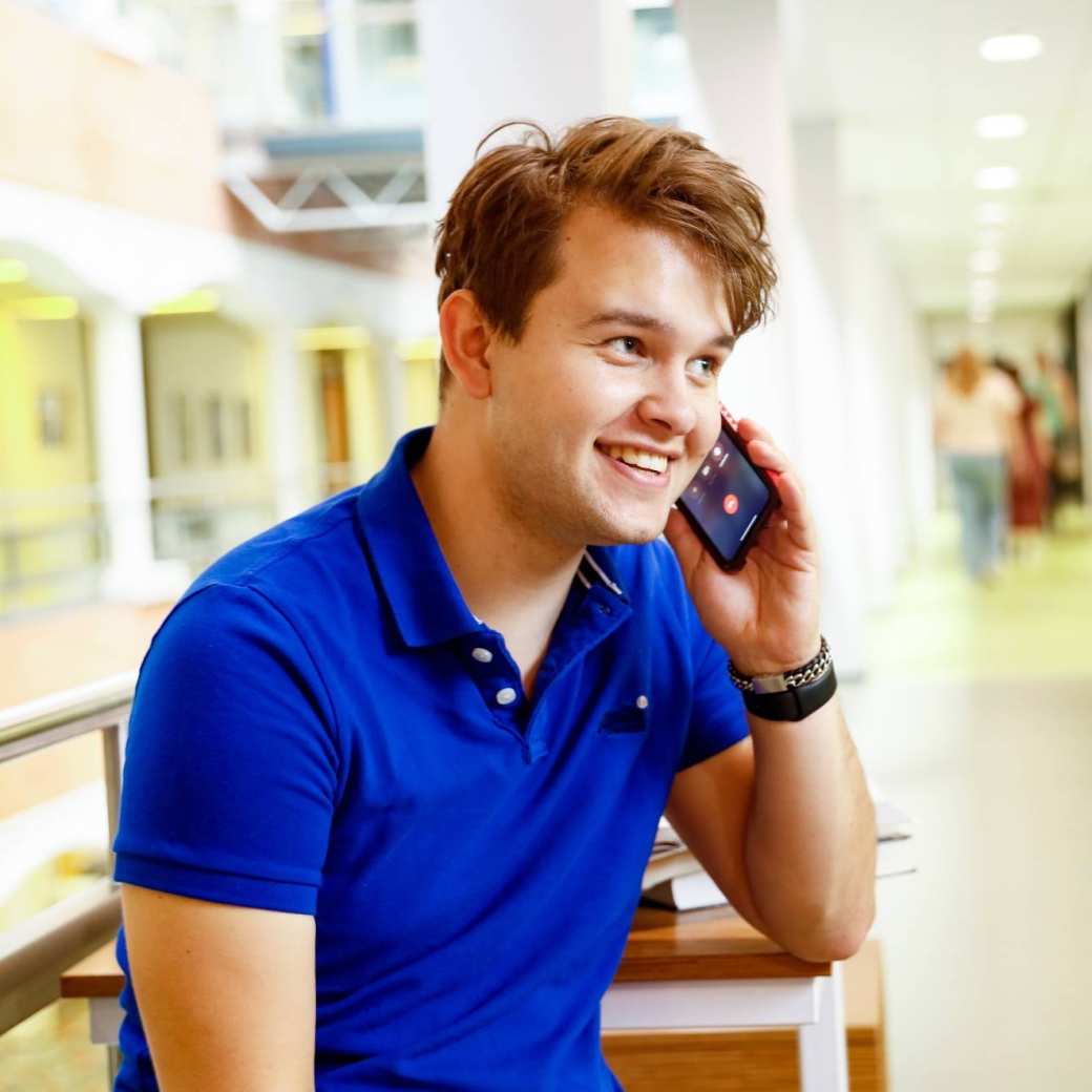 man bellen telefonisch overleg student hal gang