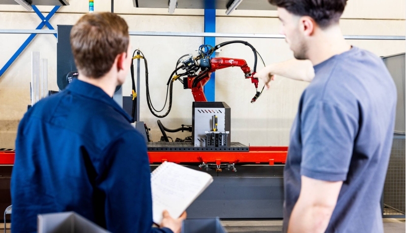 Technische Bedrijfskunde studenten Jort en Derk samen bij robot arm.