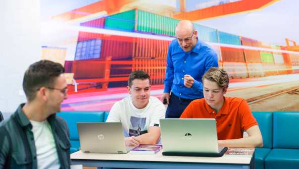 Logistics Management voltijd, LM, foto 7792, docent geeft uitleg aan tafel bij studenten in het lokaal