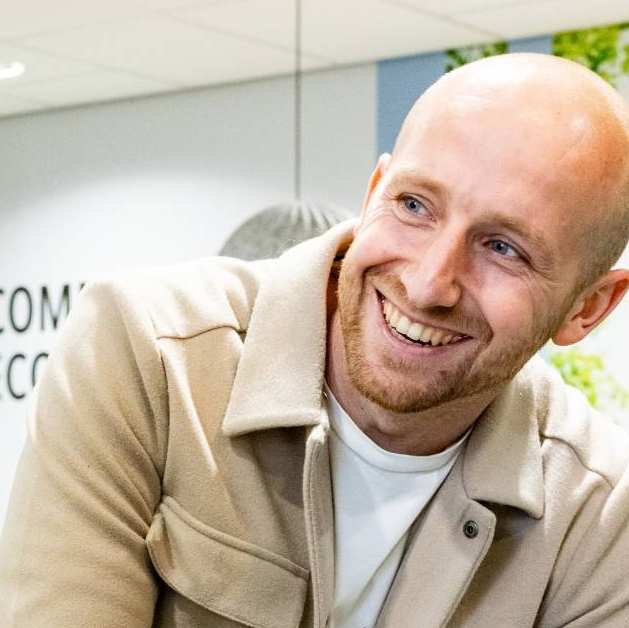 Een student van Logistiek deeltijd in de gang tijdens een pauze, lachend