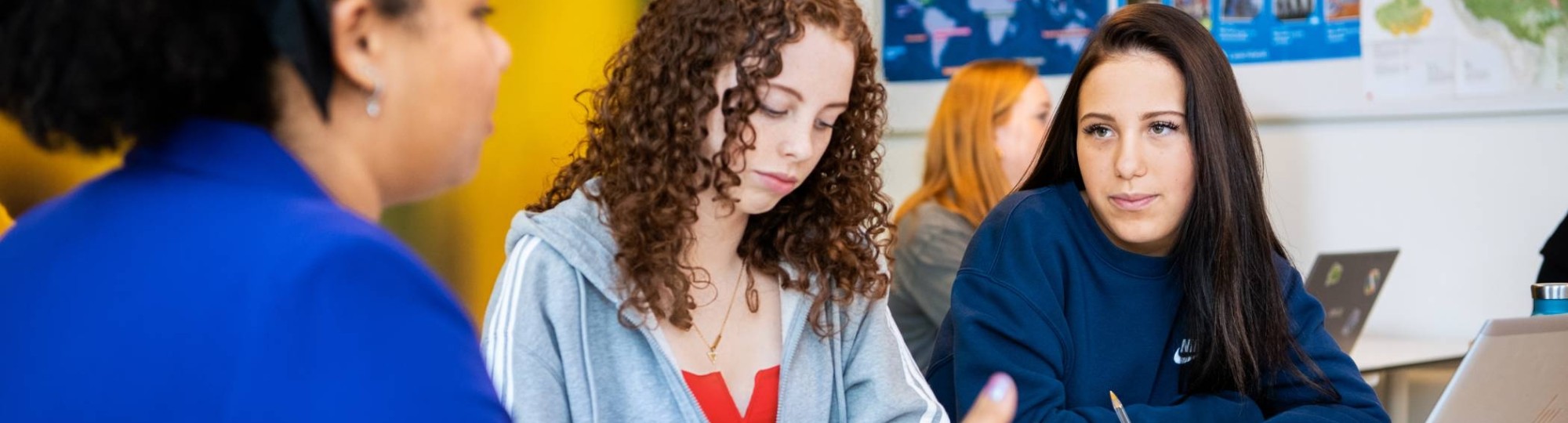 2 leerlingen krijgen uitleg aan tafel van een docenten op het Citadel College.