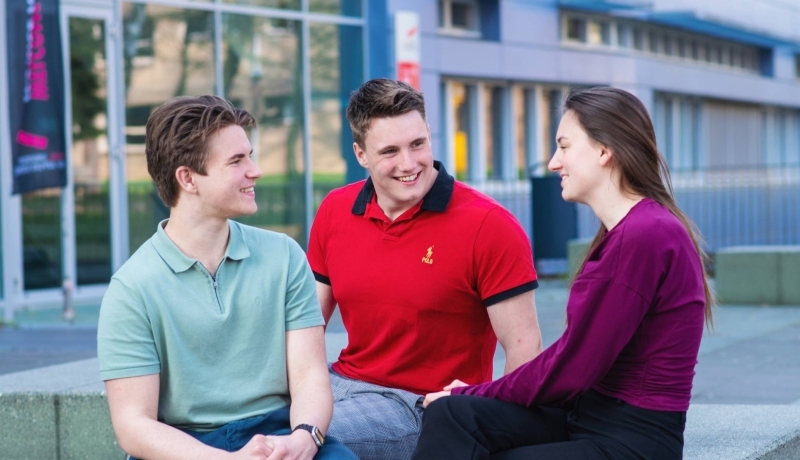 Studenten van de ad bedrijfskunde voltijd zitten samen buiten op een bankje