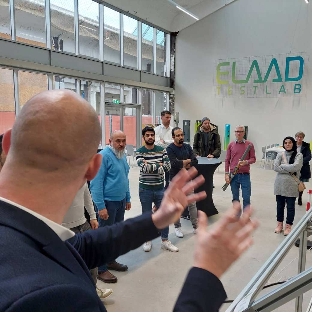 Rob Cillissen van ElaadNL legt hoogopgeleide statushouders uit hoe een laadpaal werkt.