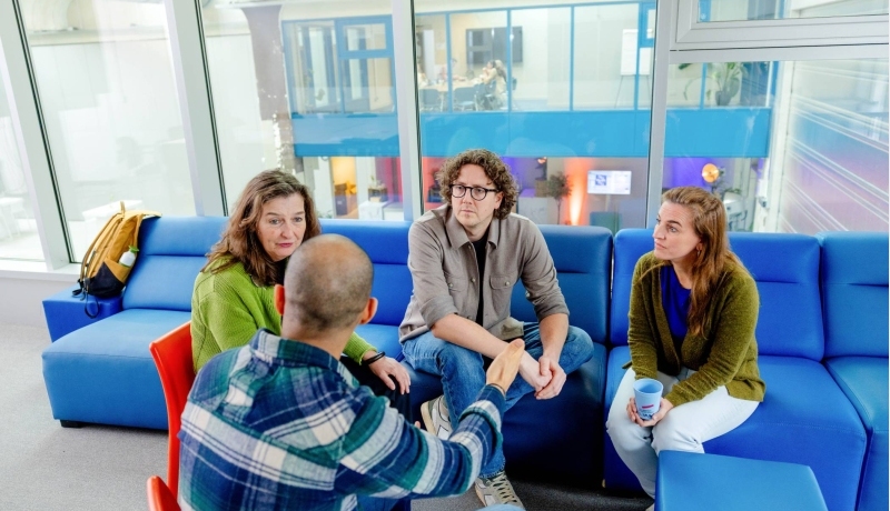 Docent kijkt via de laptop mee naar het werk van haar drie studenten.