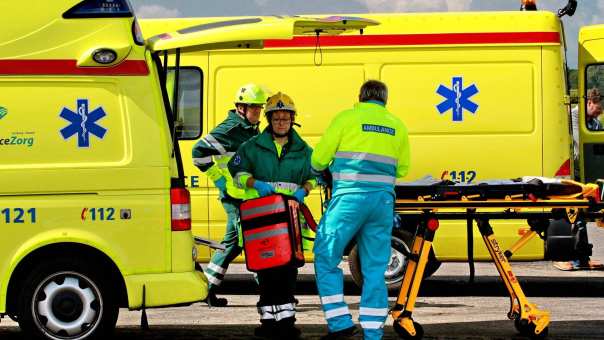 Twee ambulances waarvoor ambulanceprofessionals aan het werk zijn.