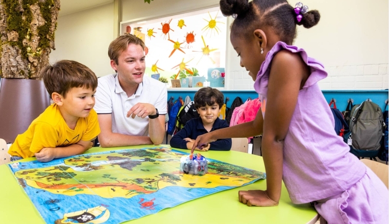 Drie kinderen spelen een bordspel in de klas. Foto van de opleiding leraar basisonderwijs 