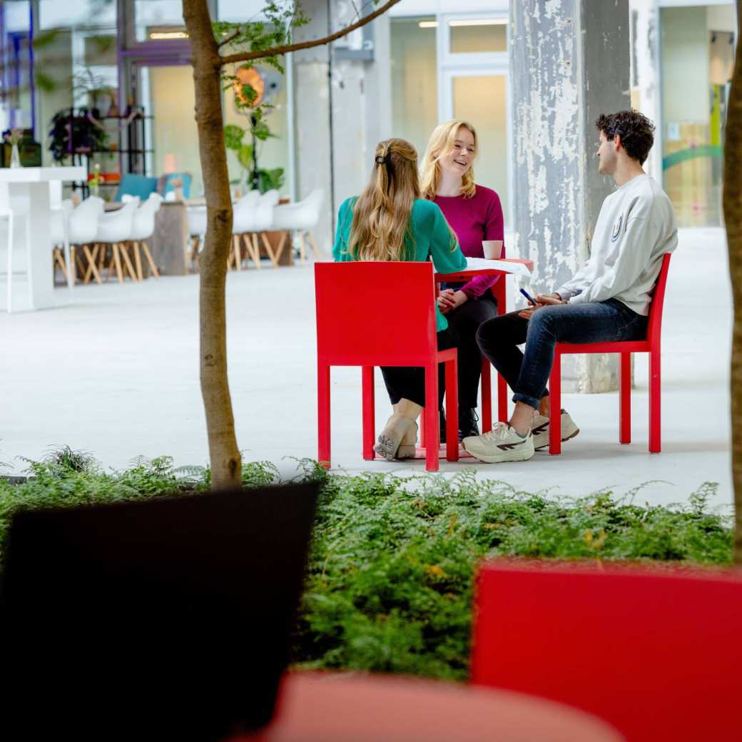 Studenten lachend in gesprek met tuin/laptop op voorgrond. Master Circulaire Economie 2024.