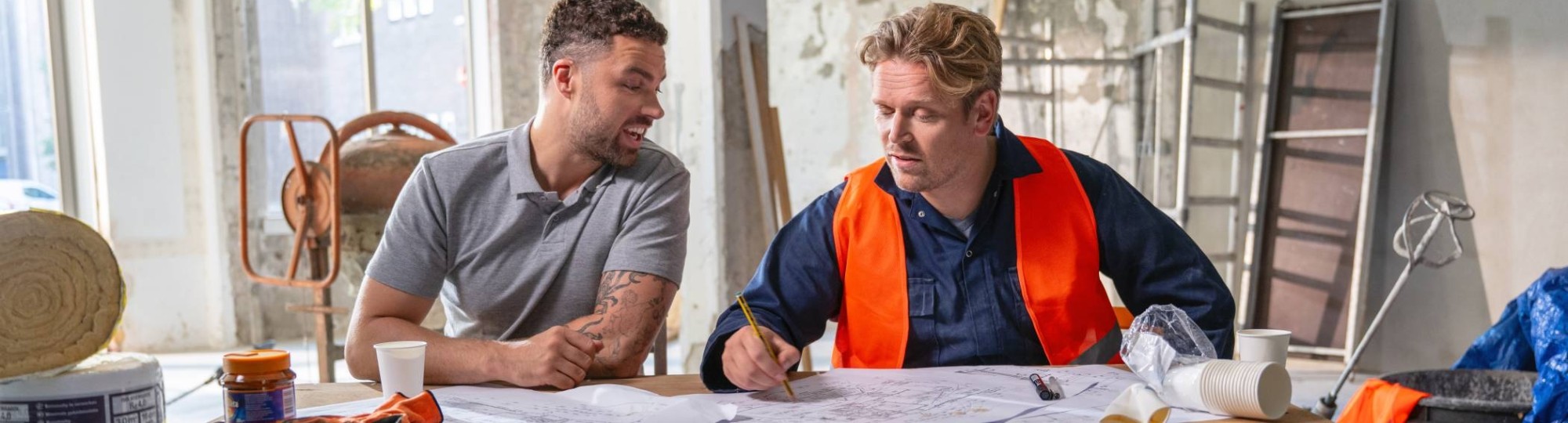 Omscholer naar techniek kijkt gelukkig naar zijn bouwtekening, met een collega ernaast.