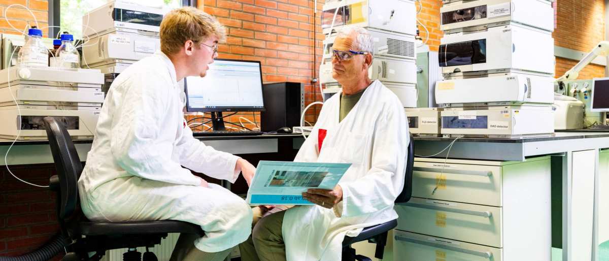 docent geeft uitleg aan student in chemie lab