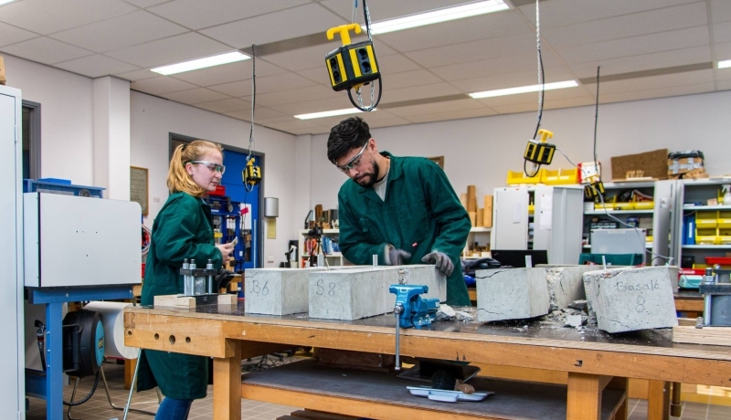 Omscholers naar bouwkunde testen beton in het betonlab.