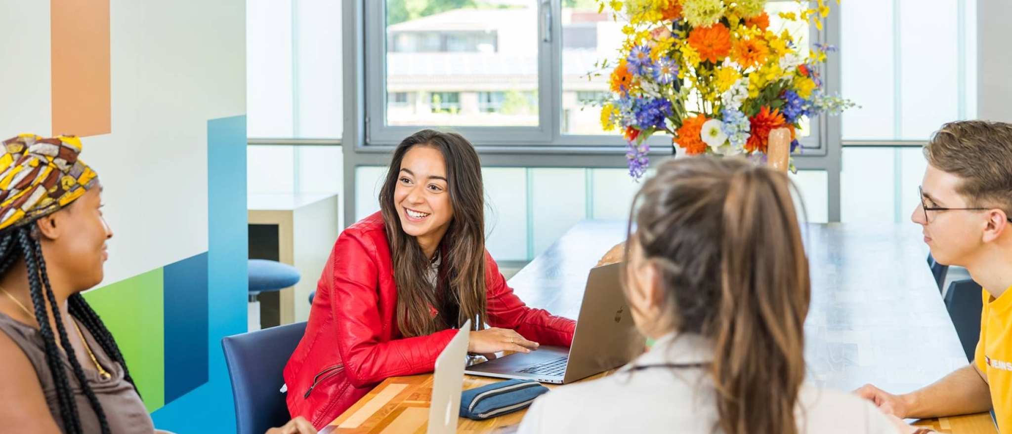 Lo-res. Groep van 4 studenten in overleg aan tafel in algemene ruimte HAN. 
