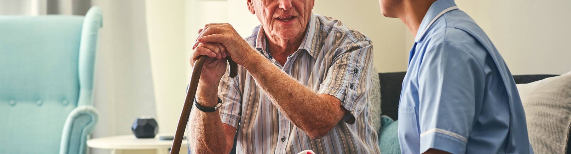 Oudere man met zorgverlener in gesprek aan bed