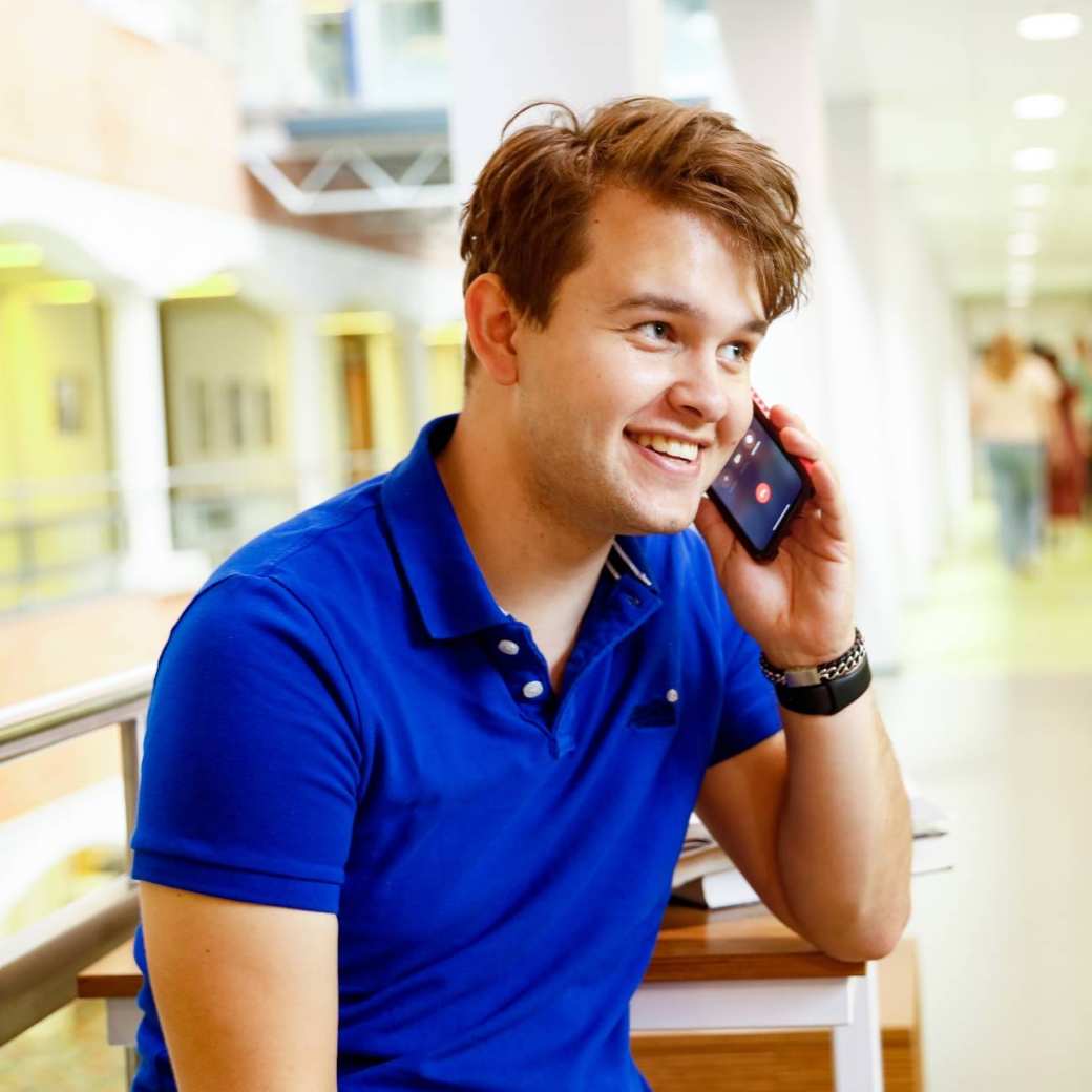 man bellen telefonisch overleg student hal gang
