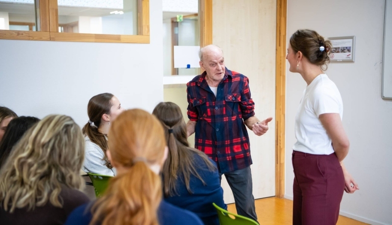 taalambassadeur Michel spreekt met bezoekers van de workshop Beperkte basisvaardigheden en structurele geldzorgen. Hij heeft een kaal hoofd en draagt een rood en zwart geruit blouse.