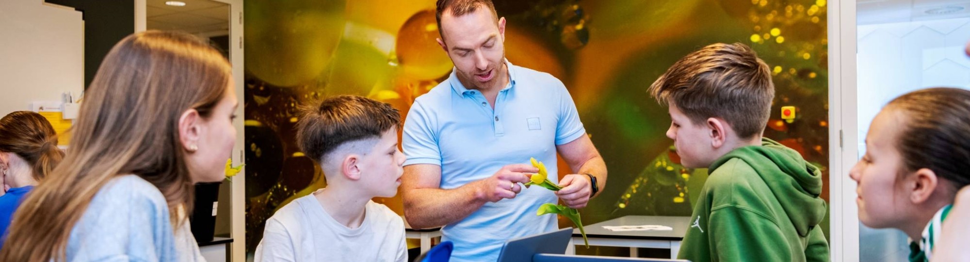 Docent Niels Janssen geeft uitleg over een bloem aan 4 leerlingen op het Citadel College.