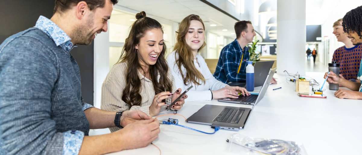 Docent en studenten cmd in overleg met prototype, lachend.