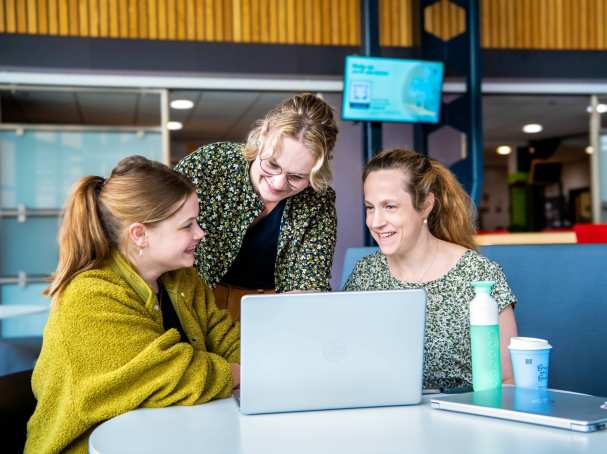 3 studenten zijn aan het overleggen met elkaar achter de laptop