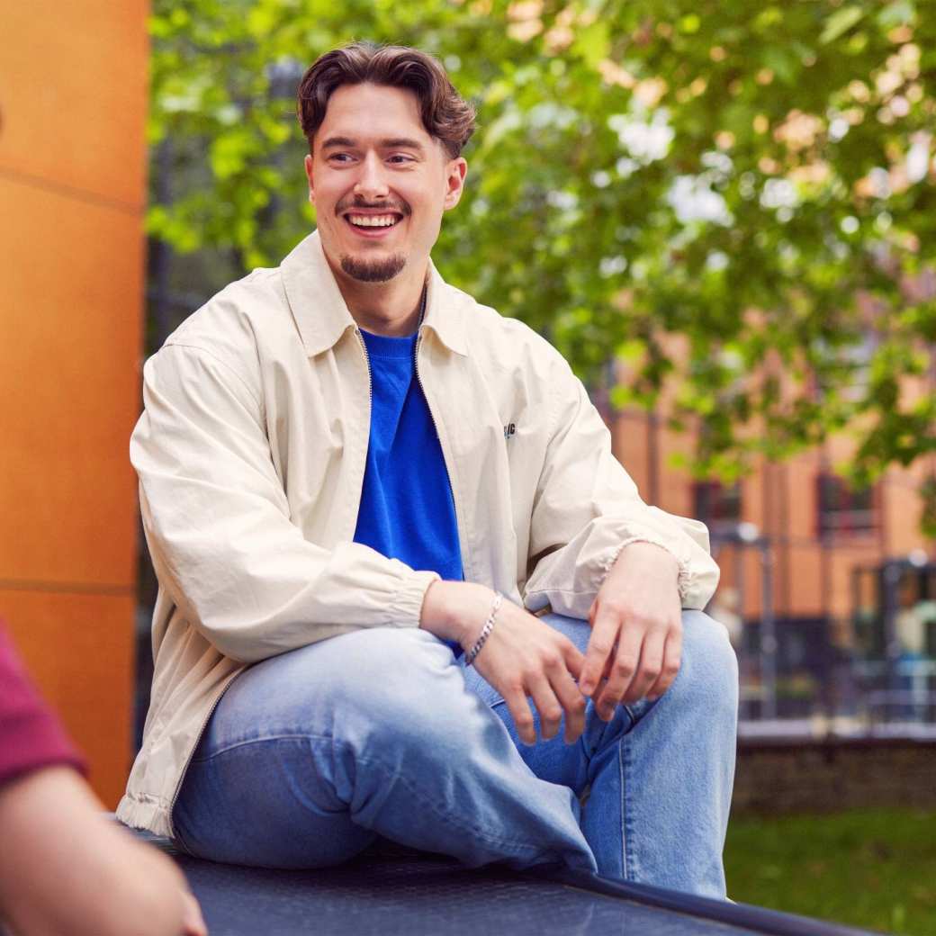 werving voltijd campagne, student met sikje zit op een picnictafel in de binnentuin.