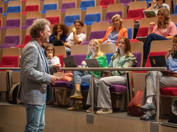 Docent geeft hoorcollege en heeft interactie met de studenten. 