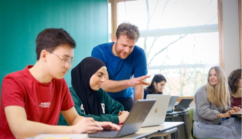 Studenten kijken lachend naar een iPad