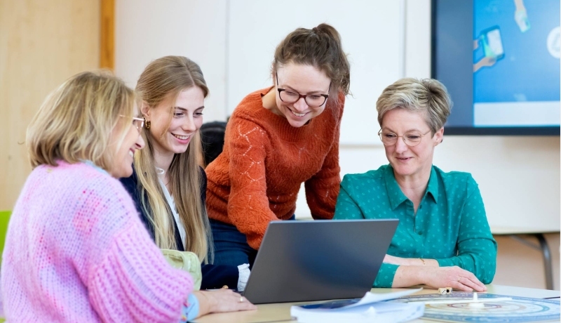 Vier studenten kijken samen naar het scherm (laptop). 