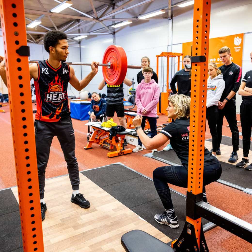 Sportstudent krijgt een instructie bij gewichtheffen