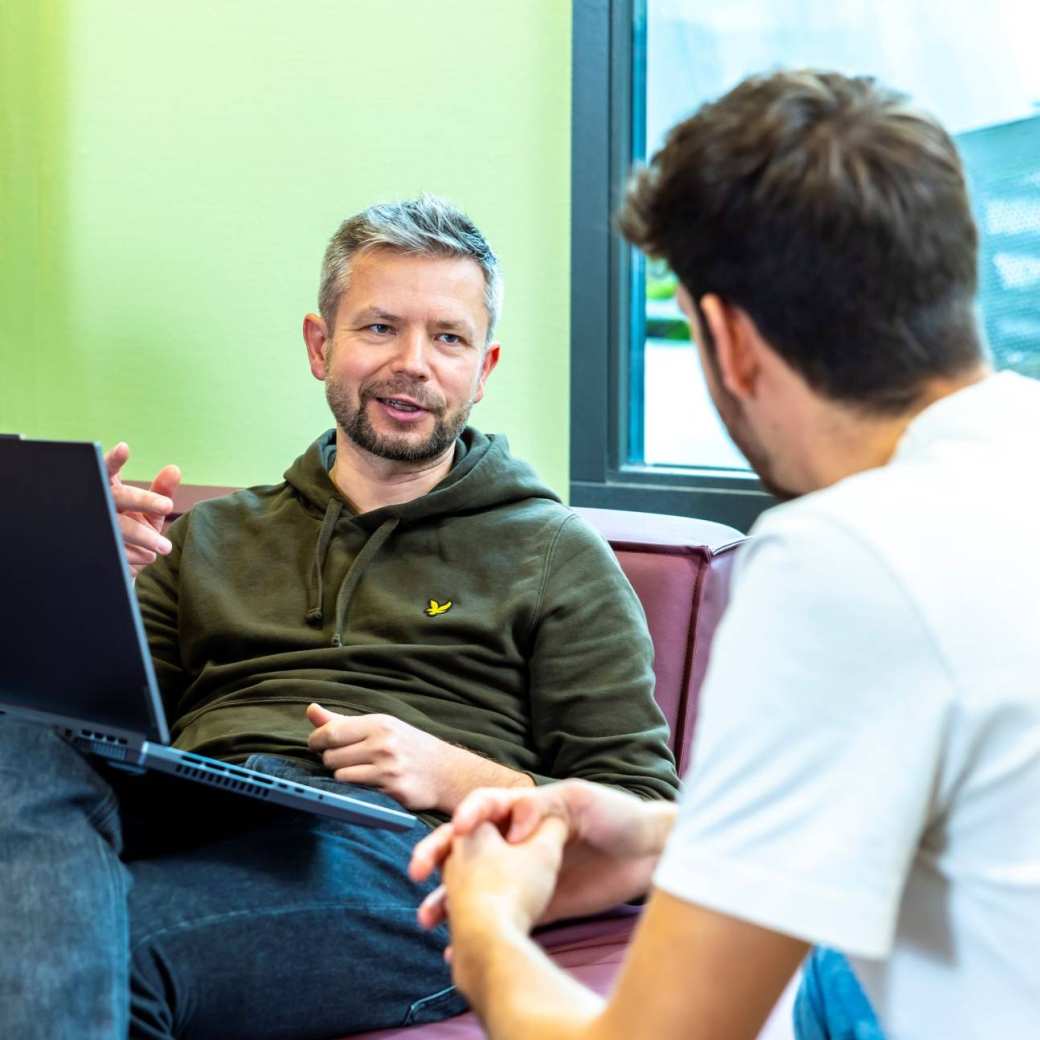 Werkgever vraagt SLIM Scholingssubsidie aan op laptop, in gesprek met werknemer.