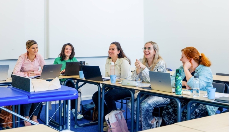 Vijf studenten zijn aan het lachen tijdens praktijkles technische thuiszorgverpleegkundige. 